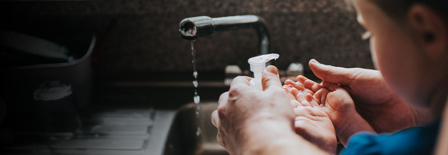 Parent showing child how to wash hands